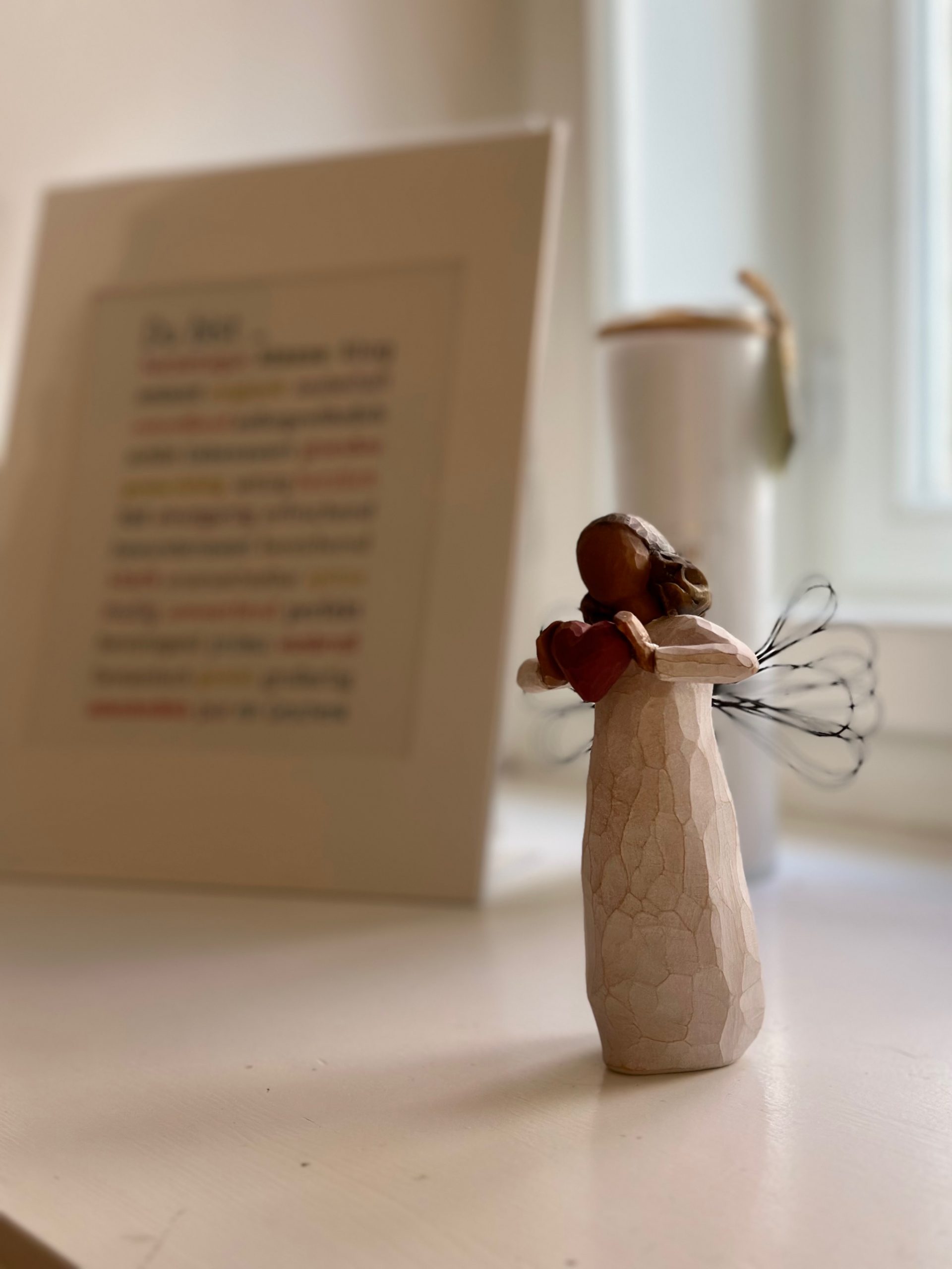 Engel mit Herz in den Händen und Text im Hintergrund